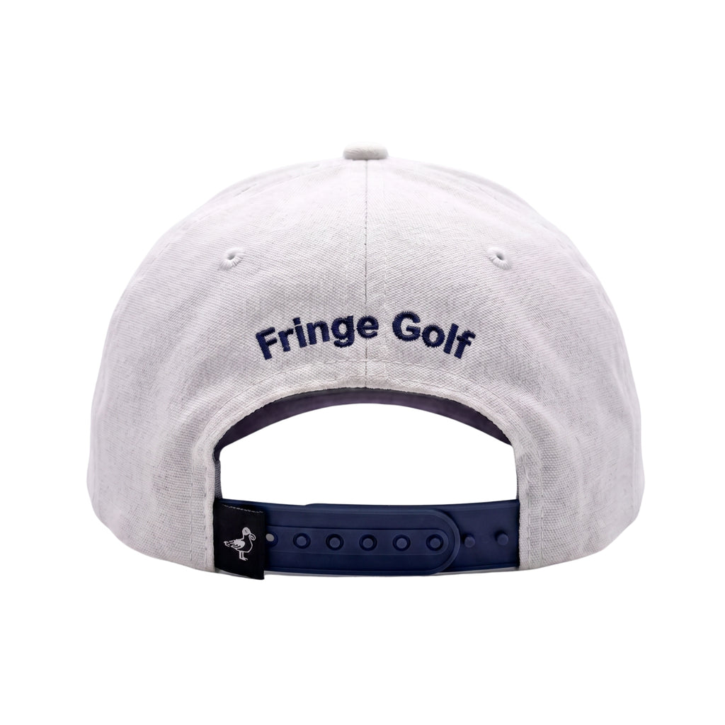 The back of a white cotton baseball cap with 'Fringe Golf' embroidered in navy blue on the crown and a navy blue adjustable strap.